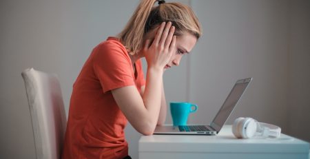 An image showing a girl with a laptop feeling stressed