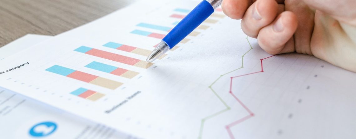 A person, who is a statistics student, is holding a pen and writing on a piece of paper with specific allocations for statistical analysis.