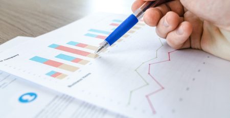 A person, who is a statistics student, is holding a pen and writing on a piece of paper with specific allocations for statistical analysis.