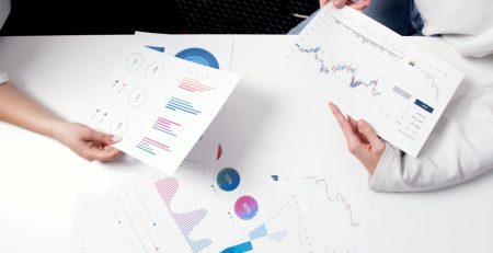 Two people sitting at a table and analyzing statistical graphs.