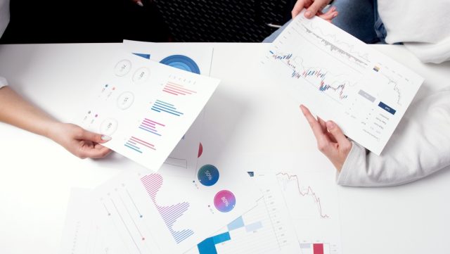 Two people sitting at a table and analyzing statistical graphs.