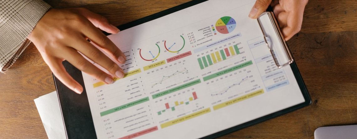 A student analyzing the differences between qualitative and quantitative data through several graphs and charts printed and pasted on a clipboard.